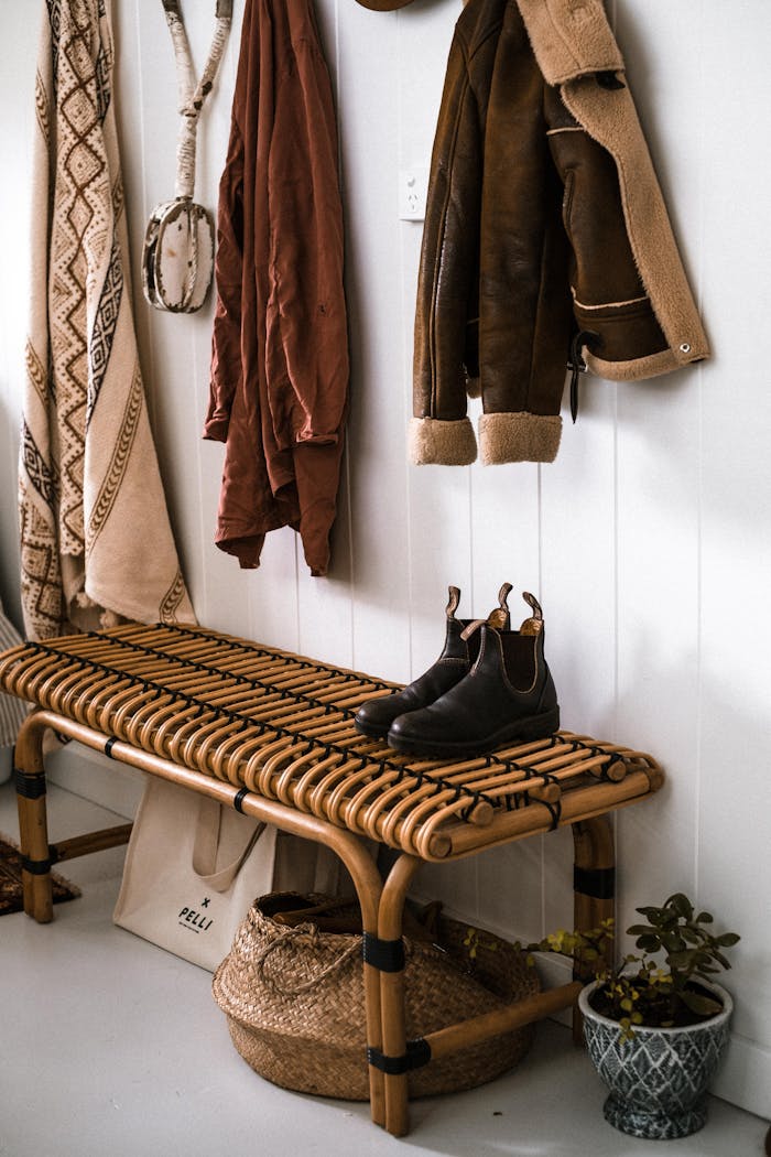 services-04 Warm and inviting entryway featuring a woven bench, hanging coats, and rustic decor on a white background.