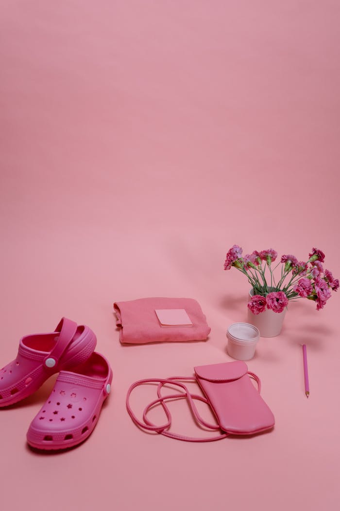 services-03 Creative flat lay of pink shoes, bag, and flowers on a pastel background.